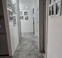 A hallway with gray tiles and photo frames in a 4-room apartment.