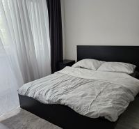 A bedroom with a bed and curtains in a 4-room apartment with a wooden decor floor.