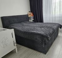 A bedroom in a 4-room apartment with a dark bed and a wooden decor floor.