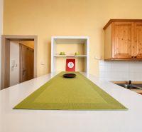 A kitchen unit with wooden cabinets and green placemats in a studio apartment.