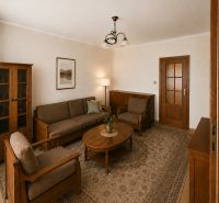 A living room in a three-room apartment with wooden furniture and a carpet.