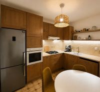 A kitchen with a wooden decor includes a refrigerator, an oven, and a coffee maker in a 3-room apartment.