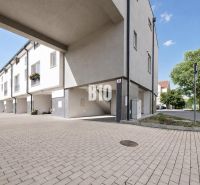 Exterior of the Holiday Apartment in Nitra with a paved courtyard and green vegetation.
