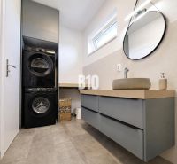 Bathroom in a holiday apartment with a washing machine, dryer, and wooden decor flooring.
