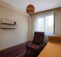 A room in a 3-room apartment with a sofa, a shelf, and a carpet, a view of the street.