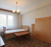 A bedroom in a 3-room apartment with a bed and a table, with a traditional carpet.