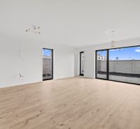 A spacious room in a family house with a wooden decor floor and large windows.