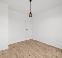 Empty room with wood-patterned flooring and a simple pendant light in a family house.