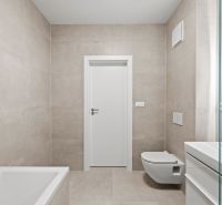 Bathroom with a bathtub, mirror, and wall-mounted toilet in a family house.