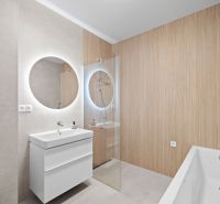 Bathroom in a family house with a bathtub, sink, and illuminated mirror.