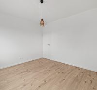 Empty room in a family house with wood-patterned flooring and a pendant light.