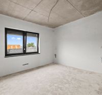 An empty room in a family house with unfinished concrete floor and ceiling.