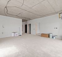 An empty room in a family house with a concrete floor and electrical cables on the ceiling.
