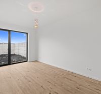 Interior of a room in a family house with wood-patterned flooring and a large window.