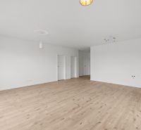 A spacious room in a family house with a wooden decor floor and white walls.
