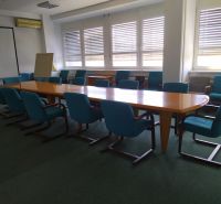 An office with a conference table and blue chairs on a carpet.