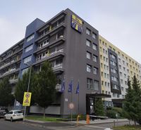 Offices in Bratislava - Ružinov on a busy street, next to greenery and parking.