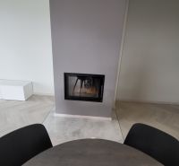 Fireplace, round table, and light floor with wooden decor in a 3-room apartment.