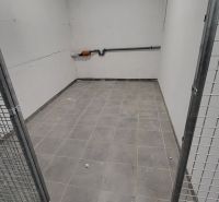 A cage-like cellar in the basement of a 3-room apartment, with brick walls and tiled floor.