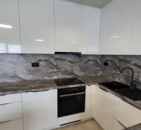 A kitchen with a sink and a stovetop; part of a 3-room apartment with a marble decor.
