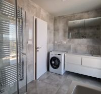 Modern bathroom with a washing machine in a 3-room apartment, gray tiles and a shower corner.