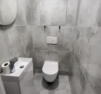 Gray bathroom with a toilet and a small sink in a 3-room apartment.