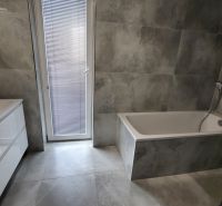 Bathroom with a bathtub and a sink, tiles in gray tones, part of a 3-room apartment.