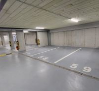 Parking spaces in an underground garage with numbers marked on the concrete floor.