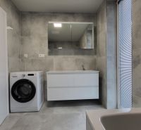 Bathroom in a 3-room apartment with a washing machine, sink, and mirror, gray tiles.