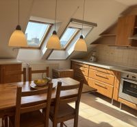 A kitchen in a 4-room apartment with a wooden decor floor and slanted roof windows.