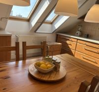 A kitchen in a 4-room apartment with a wooden decor floor and skylights.