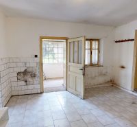 The ground floor of a family house with tiles, old doors, and a view into a pantry with shelves.