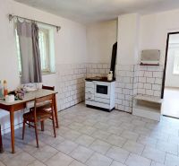 A kitchen in a family house with wooden decor, a dining table, and tiles.
