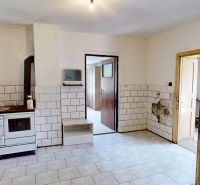 An older kitchen with a stove in a family house, white tiles on the walls.