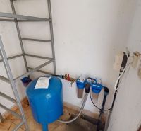 Storage space with a pressure tank and water filters in a family house.