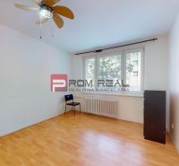 An empty room with a wooden-patterned floor and a large window in a 3-room apartment.