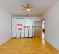 A room with a wooden floor decor in a 3-room apartment includes a built-in wardrobe and a fan.