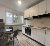 A kitchen in a 2-room apartment with a round table, four chairs, and a kitchen unit.