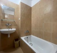 A bathroom with a white bathtub and sink in a two-room apartment.