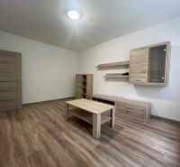 Living room in a two-room apartment with wood-decor furniture and a wood-patterned floor.