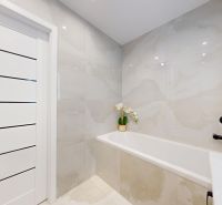 Bathroom in a 3-room apartment with a bathtub, white doors, and black hardware.