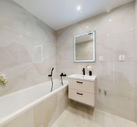 Bathroom with a bathtub, sink, and illuminated mirror in a 3-room apartment.