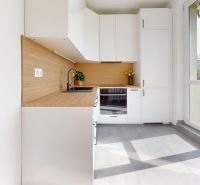 A kitchen in a 3-room apartment with white cabinets and a wood-patterned floor.