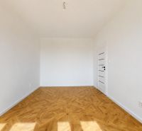 A room in a 3-room apartment with a wooden decor floor, white walls, and doors.
