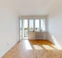 A room with a bright interior, a balcony, and a wooden decor floor in a 3-room apartment.