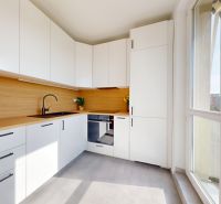 A kitchen in a 3-room apartment with white cabinets and a wood-patterned floor.