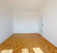 An empty room with white walls and a wooden decor floor in a 3-room apartment.