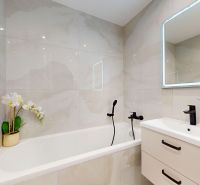 Bathroom in a 3-room apartment with a bathtub, mirror, and decorative flowers.