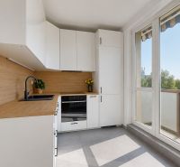 A kitchen in a 3-room apartment with white cabinets and a wood-patterned floor.