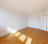 A spacious room in a 3-room apartment with a wooden decor floor and white walls.